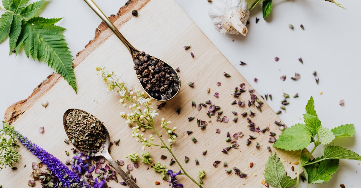 A top view of dried and fresh herbs on a wooden board, perfect for culinary and medicinal uses.